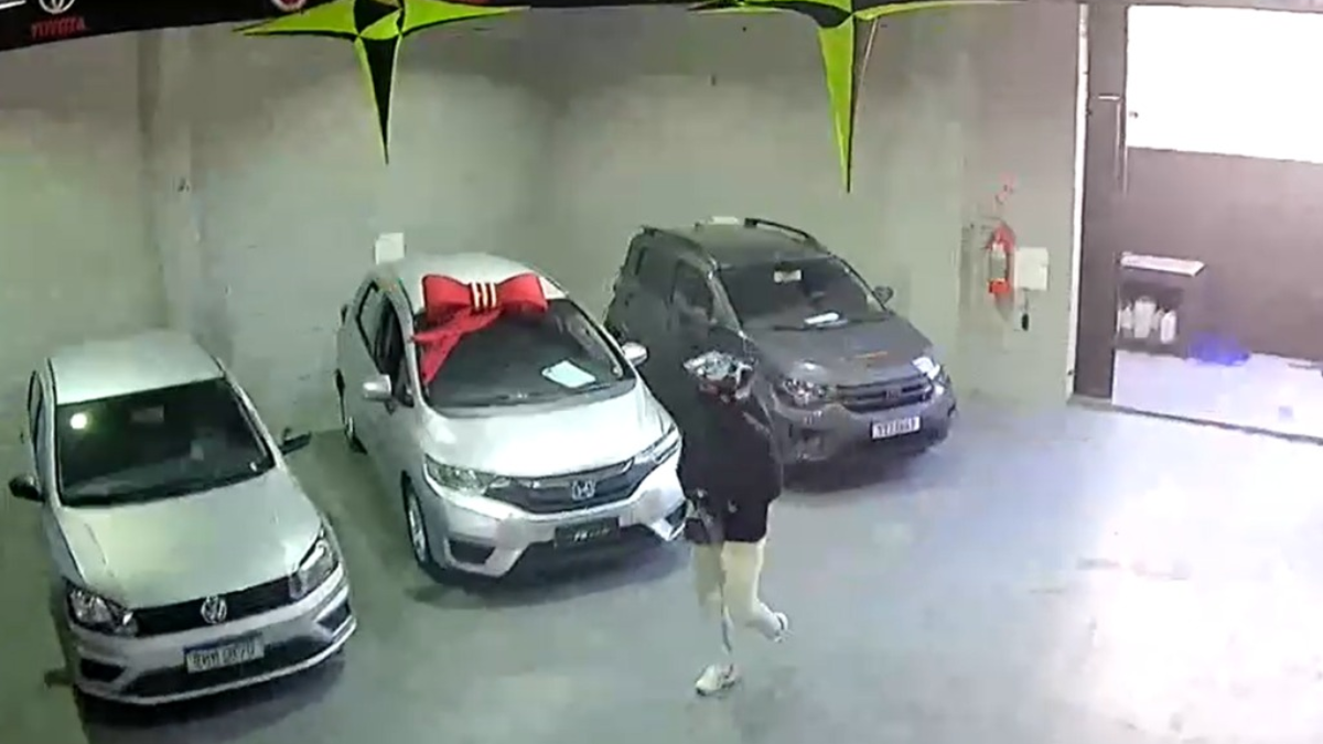 loja de veículos assaltada em Hortolândia: Câmeras de segurança mostram uma loja com carros estacionados em um ambiente fechado, enquanto criminosos armados fazem um assalto em Hortolândia e trancam funcionário no banheiro.