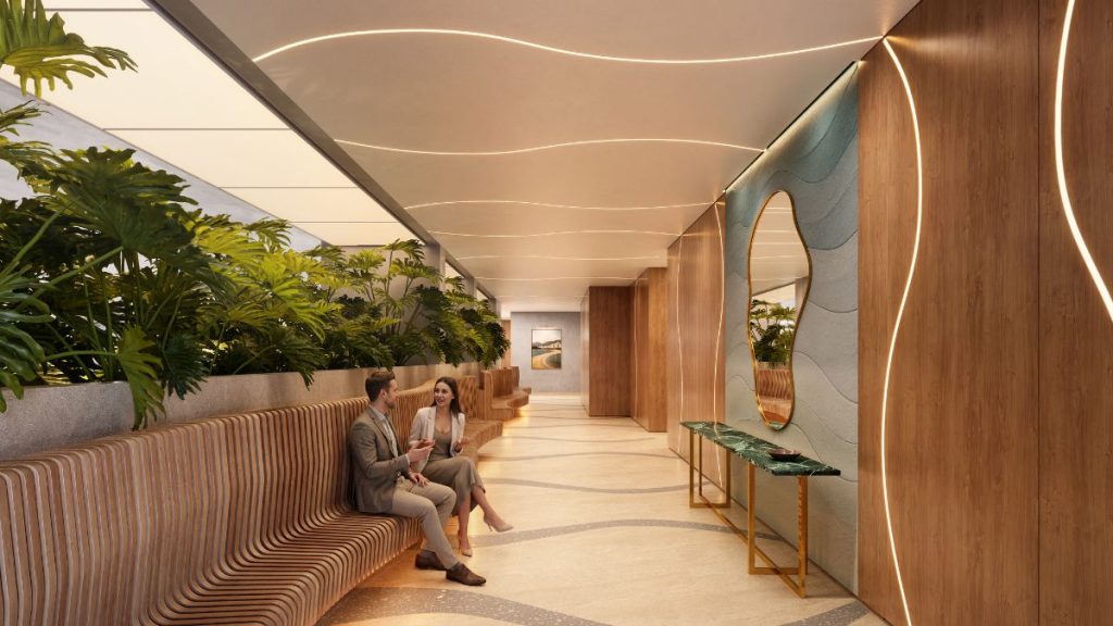 Hall decorado com iluminação embutida, paredes em madeira e paredes claras, com plantas em jardineiras e dois moradores sentados, mostrando a área de convivência do Gran Canal Residence em Santos.