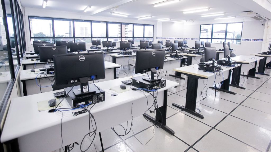 Sala de informática da Unimes em Santos, com várias mesas e computadores, em foto ilustrativa sobre reconhecimento de títulos de faculdade paraguaia investigada — Foto: Unimes fraude de títulos