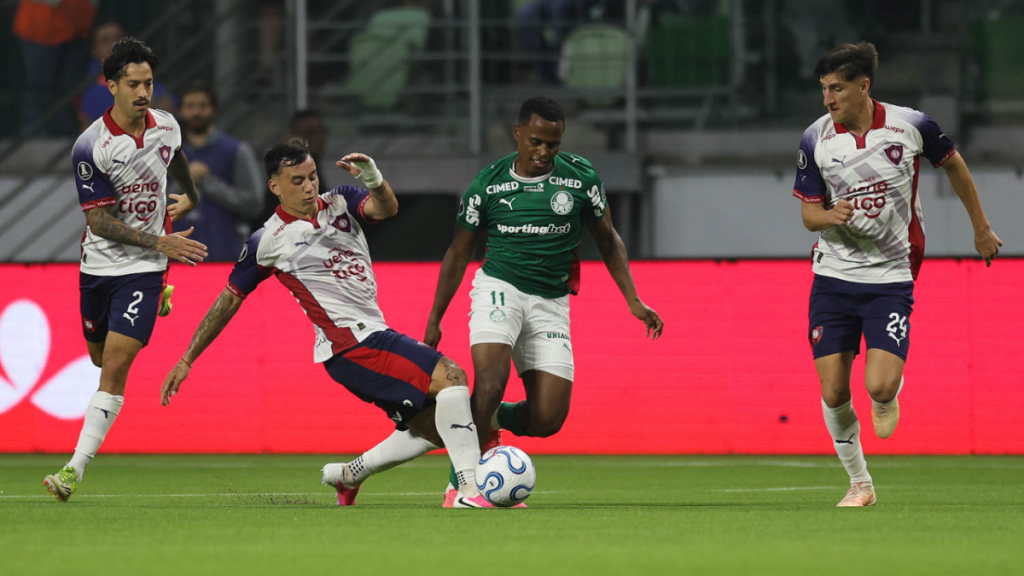 Abel Ferreira observa partida do Palmeiras em empate pela Libertadores, com jogadores em campo disputando bola durante o jogo contra o Cerro.