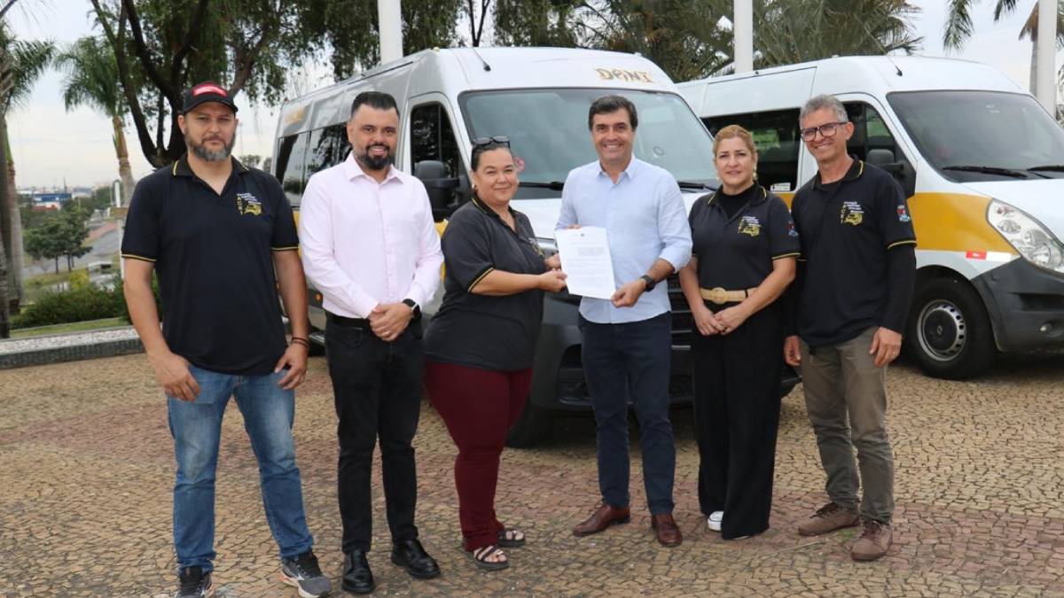 Equipe em frente a veículos do transporte coletivo em Indaiatuba, com documento entregue em solenidade de atualização das regras do transporte coletivo e eliminação de custos para permissionários.