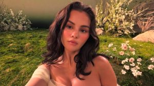 Selena Gomez em foto ao ar livre, com jardim e flores ao fundo, em contexto de notÃ­cia sobre suposta fraude milionÃ¡ria envolvendo ela e a mÃ£e.