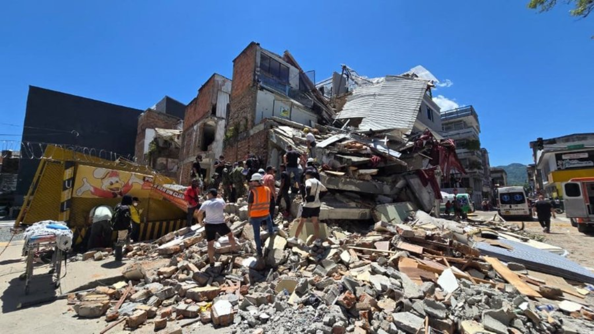 Terremoto na Colômbia: rua com prédios parcialmente destruídos, escombros e equipes de resgate caminhando entre destroços após o tremor