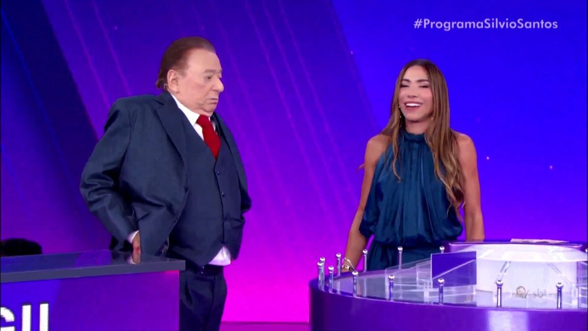 Raul Gil e Patrícia Abravanel durante participação no SBT, no palco do programa Programa Silvio Santos, com clima de brincadeira e sorrisos. Raul Gil em pé ao lado dela.