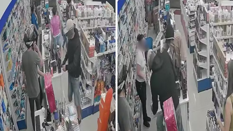 assalto a farmácia em Mogi Guaçu: Câmeras de segurança registram dupla armada em corredor de farmácia, com pessoas rendidas entre prateleiras, durante o assalto em Mogi Guaçu.