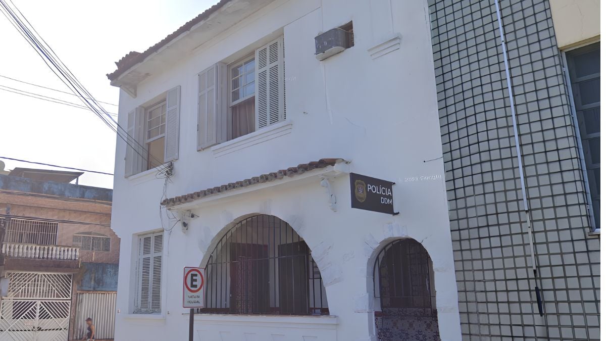 Prédio da Polícia Civil em São Vicente, com fachada branca e janelas em grade, visto em reportagem sobre a situação de Grávida é agredida em São Vicente, de três meses.