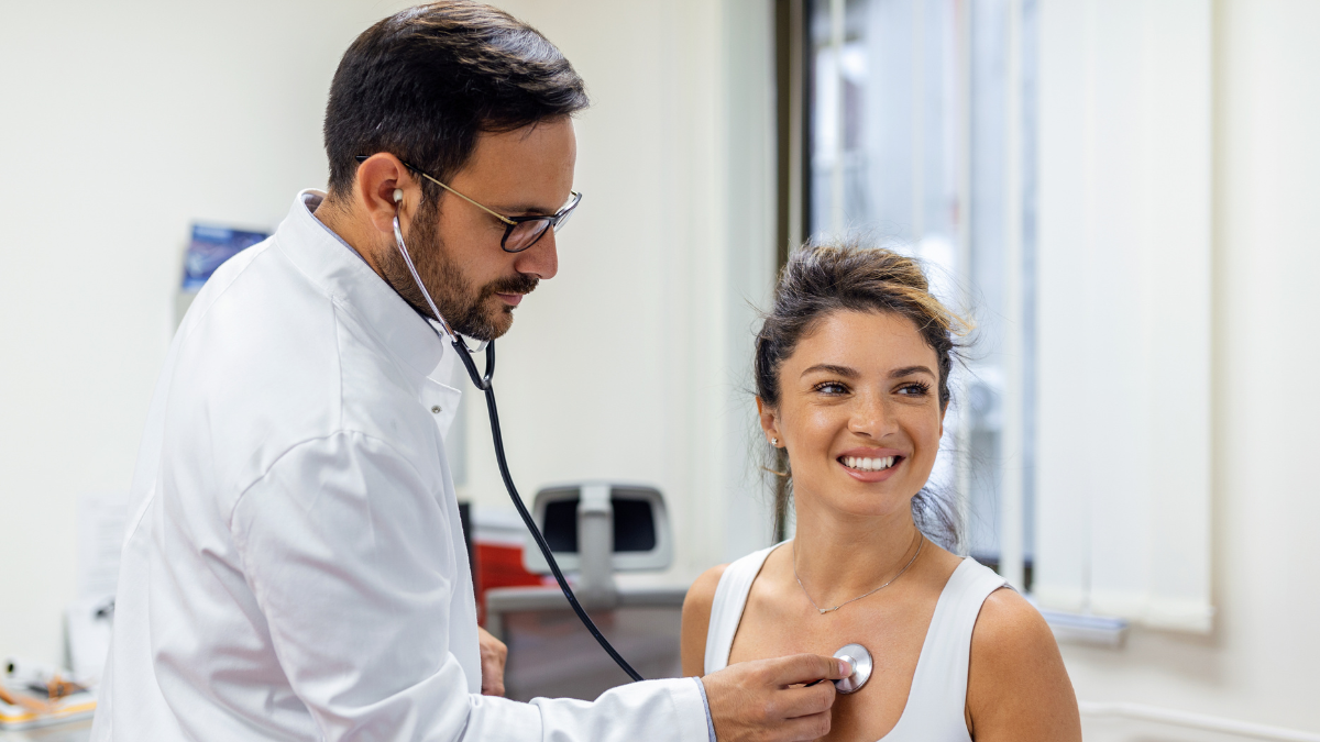 Dia do Cardiologista: médico examina uma paciente em consultório, discutindo cinco mitos sobre doenças cardiovasculares que precisam ser esclarecidos, com estetoscópio ao redor do pescoço.