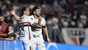 São Paulo Sul-Americana: Jogadores do São Paulo comemoram durante partida de futebol, com torcida desfocada ao fundo, após vitória que garante confronto nas quartas de final da Sul-Americana contra o Boca Juniors.