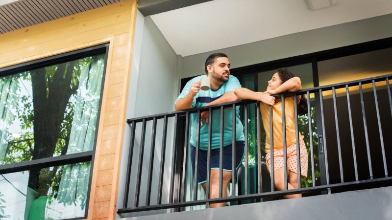 regras de condomínios: Papo de Síndico: veja regras para obras e mudanças na fachada em condomínios, com moradores conversando na varanda de um prédio residencial.