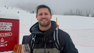 Jonas Sulzbach aparece em foto ao ar livre, em clima de neve, com roupa de frio e colete de viagem, sorrindo ao lado de uma área com gelo e estrutura ao fundo.