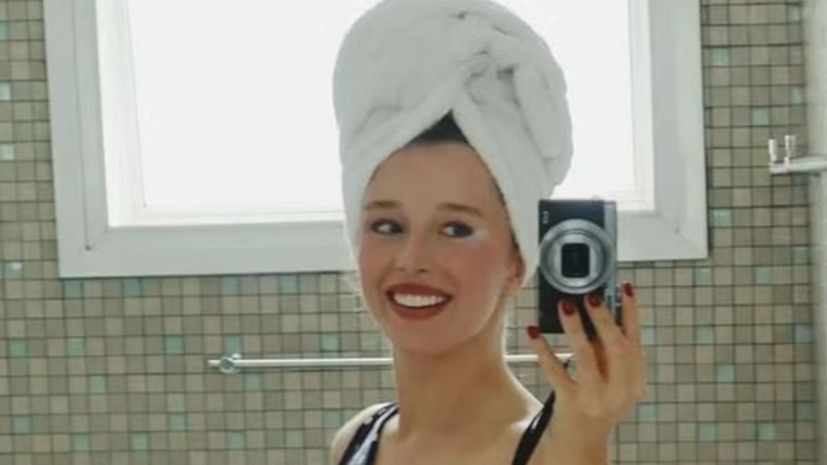 Duda Reis aparece em um vídeo em frente ao espelho, sorrindo e usando touca branca de cabelo, enquanto lista hábitos importantes para sua saúde mental. Foto no banheiro, com azulejos ao fundo e celular na mão.