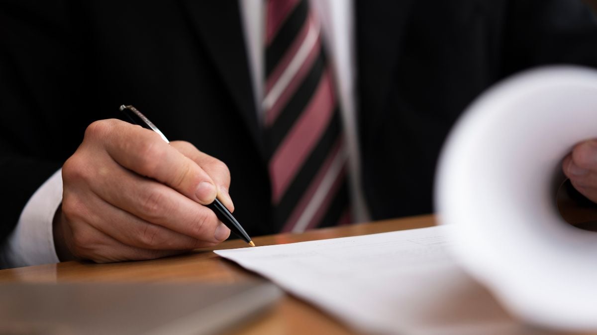 Mão de advogado assinando documentos sobre recuperação judicial, em escritório, com foco em papel e caneta; tema de que a recuperação judicial não é falência.