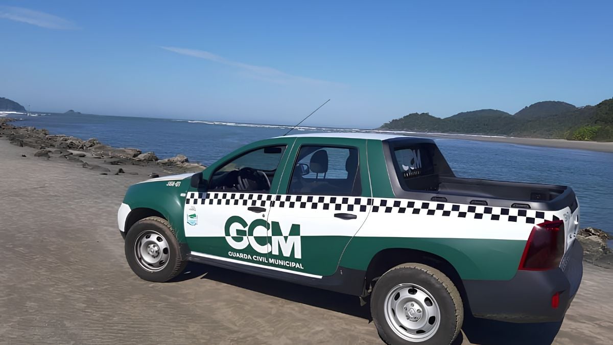 Mulher chama GCM de macaca em Peruíbe: Veículo da GCM (Guarda Civil Municipal) estacionado na orla de Peruíbe, com o texto GCM e uma faixa preta e branca na lateral, em cenário de praia ao fundo.