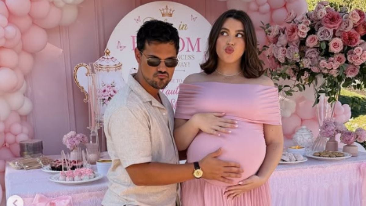 Chá de bebê Tay Lautner: Taylor Lautner e Tay em chá de bebê da primeira filha, com mesa decorada em tons de rosa e detalhes do enxoval ao fundo.