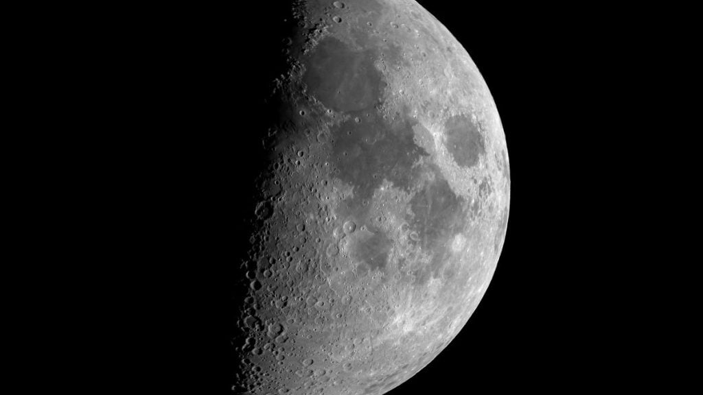 Vista em preto e branco da Lua parcialmente iluminada, com aparência de eclipse, em um cenário escuro que sugere condições meteorológicas favoráveis para observar o fenômeno no céu. eclipse lunar no Brasil