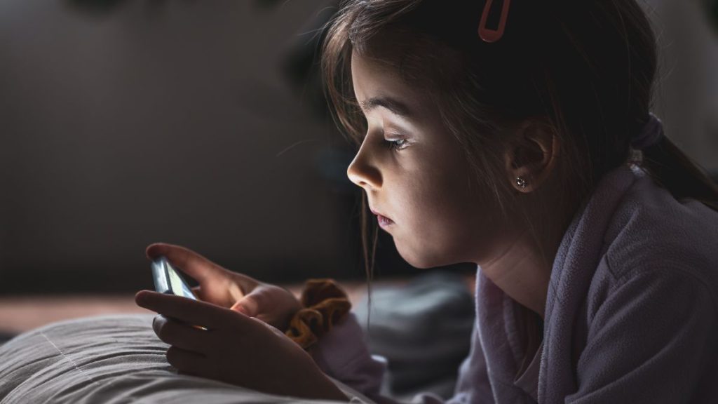 Jovem usando o celular em casa, com atenção à privacidade de menores de 16 anos em plataformas como o TikTok. Tiktok multa em contexto de restrições de dados.