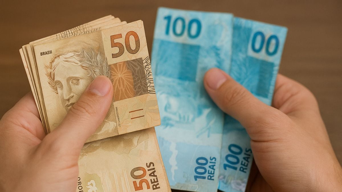 Mãos segurando notas de dinheiro do Brasil, incluindo cédulas de 50 e 100 reais, com foco em reajuste do salário mínimo e valores projetados para 2027.