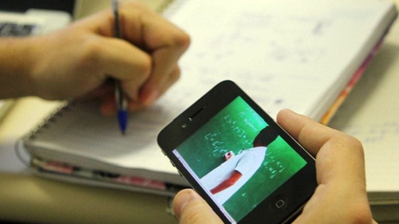Enem 2026: como montar um cronograma de estudos com a preparação para a prova, enquanto uma pessoa usa um celular ao lado de caderno e lápis sobre uma mesa, em ambiente de estudo.