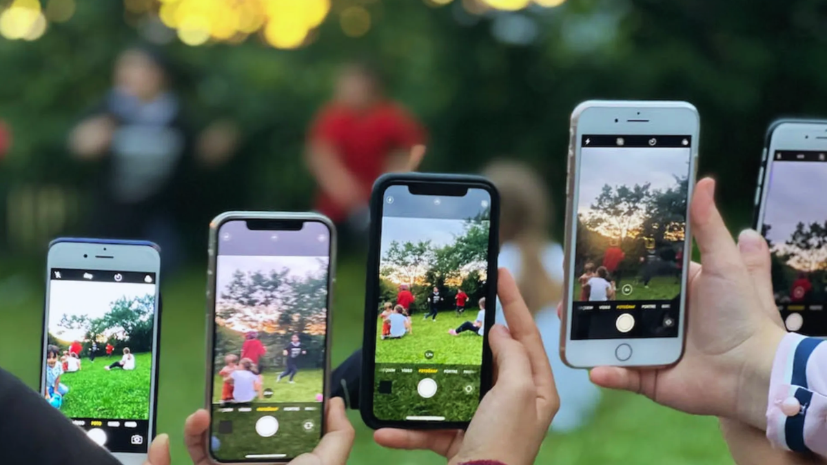 Pessoas segurando vários modelos de iPhone mostram a câmera em tela ao ar livre, com efeito de transmissão ao vivo em vídeo; novo recurso do iphone vídeo ao vivo.