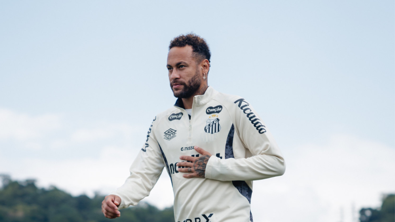 Neymar Palmeiras: Neymar em treino do Santos, com roupa oficial clara e expressão concentrada no campo, enquanto surge a informação de que o clube não deve divulgar se ele enfrenta o Palmeiras pela Copa do Brasil.