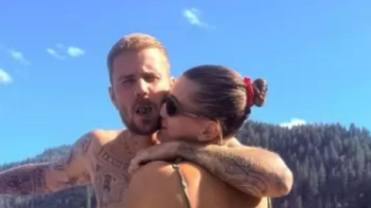 Justin Bieber e Hailey Bieber em um passeio romântico de barco, com o casal se abraçando ao ar livre ao céu azul e montanhas ao fundo; Justin e Hailey passeio romântico.