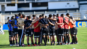 Elenco da Ponte em campo durante reunião e protesto, com jogadores agrupados em pé no gramado de estádio, indicando greve por salários atrasados.
