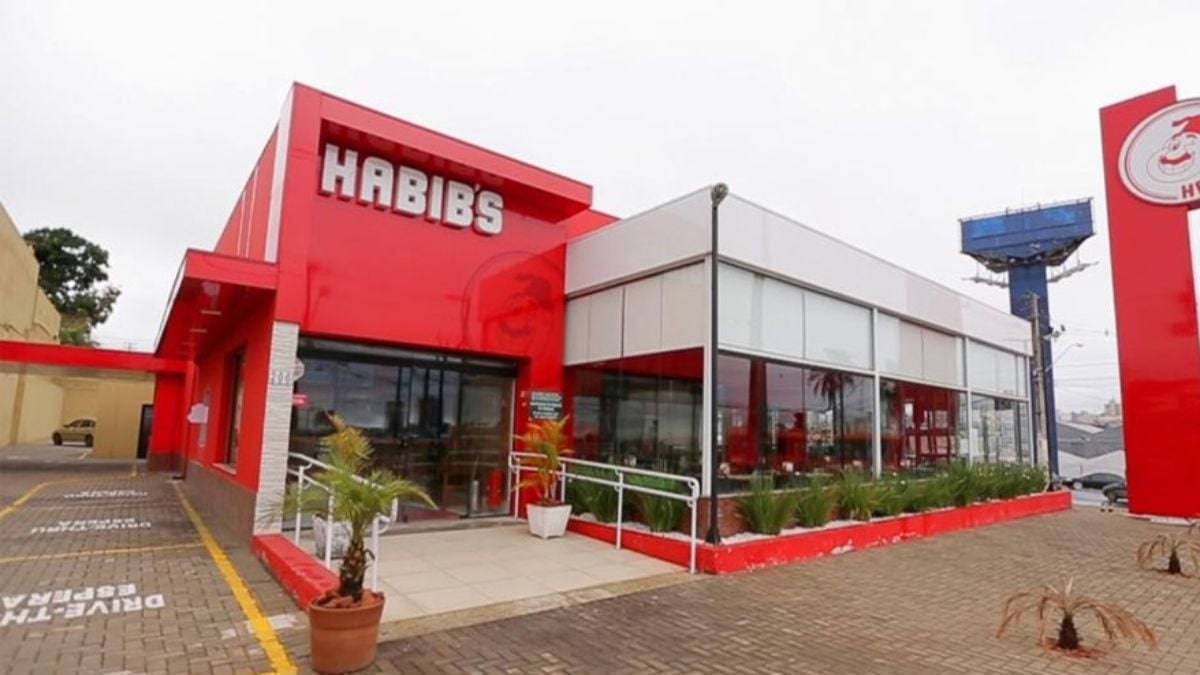 Habibs: Fachada de uma unidade do Habib's em ambiente externo, com placa “Habib’s” e áreas de entrada e estacionamento, ilustrando notícia sobre recuperação judicial após dívida de R$ 265 milhões.