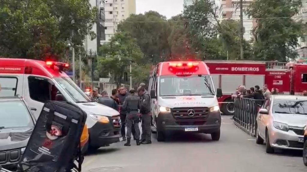 Idosa morre atropelada em Santos: Foto de carros e ambulâncias do socorro na via em Santos, com equipes de resgate ao fundo e viaturas vermelhas dos bombeiros após acidente com pedestres