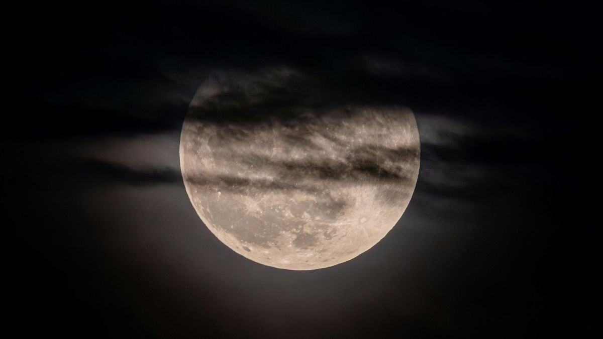 Eclipse lunar visível no céu, com a Lua parcialmente coberta e um tom avermelhado ao fundo, em uma cena noturna ideal para observar no Brasil.