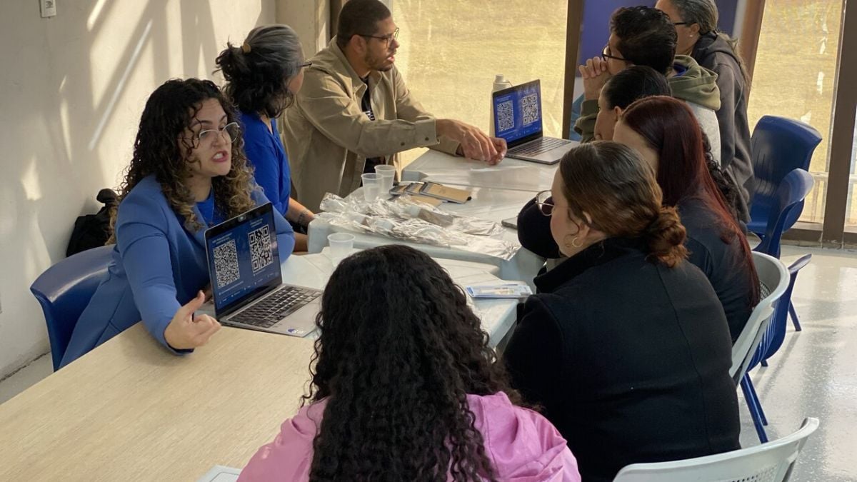 Vagas de emprego em Hortolândia: Recrutamento em Hortolândia: pessoas reunidas em uma sala durante encontro de emprego com 200 vagas nesta sexta-feira (28), conversando com equipe e consultando informações em notebooks e documentos.