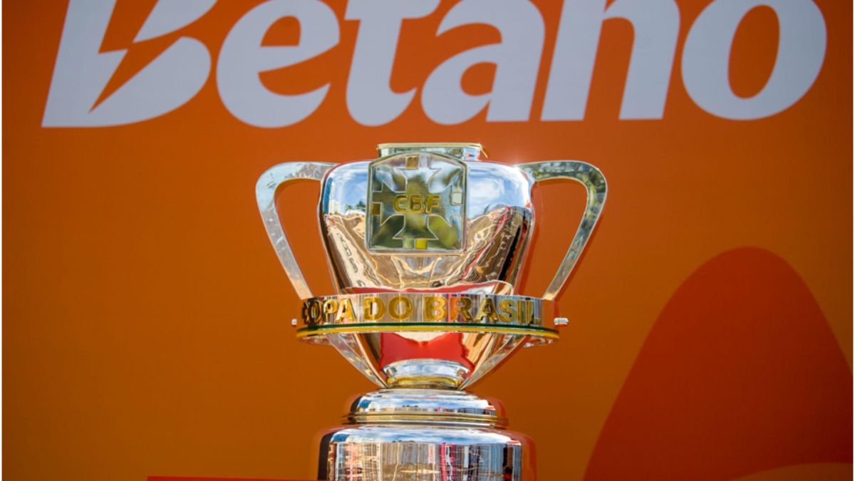 Tour da Taça da Copa do Brasil: imagem mostra a taça da Copa do Brasil em destaque, com fundo laranja e o texto “lado Brasil”, em cenário de exposição no shopping.
