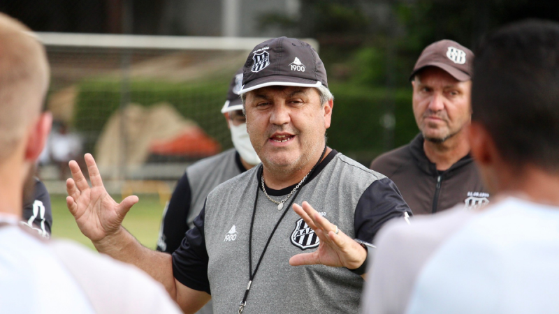 Gilson Kleina, técnico da Ponte Preta, aparece em foto durante treino, gesticulando com as mãos para jogadores ao redor.