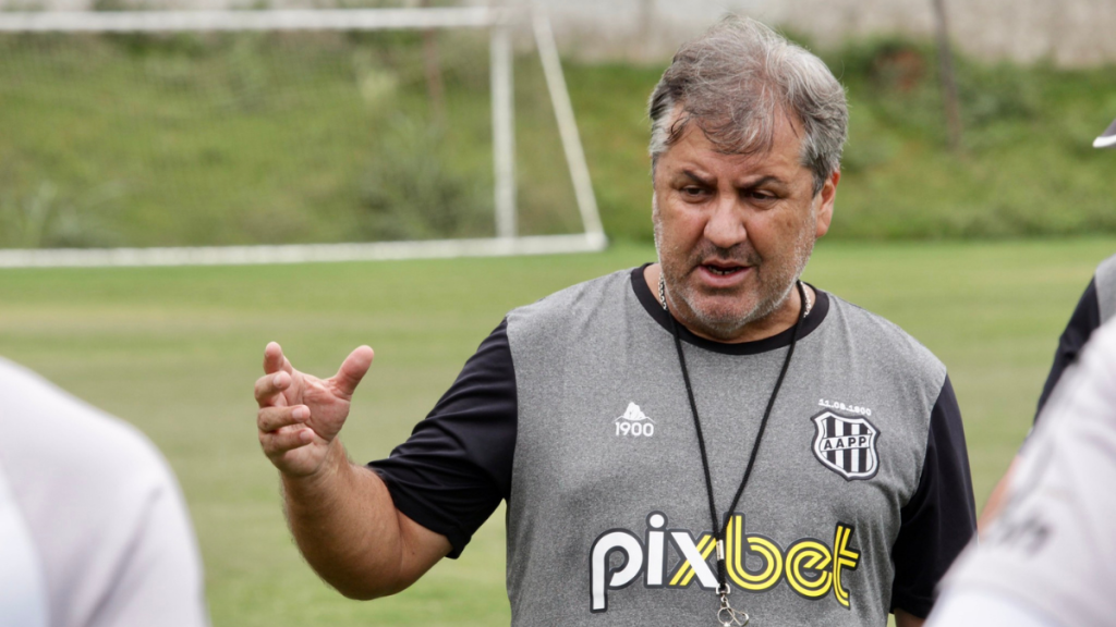 Gilson Kleina, novo técnico da Ponte Preta, aparece em treino ao ar livre com mão aberta e olhar atento, em foto de Diego Almeida.