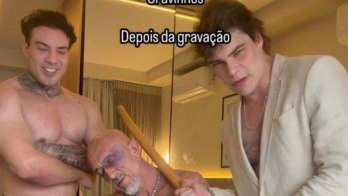 Após a gravação, dois homens em um ambiente interno, um tatuado sorrindo ao lado de outro de cabelo escuro e um terceiro sentado, em clima descontraído.