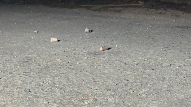 Pequenos fragmentos de material espalhados sobre o chão de concreto, em uma cena com superfície áspera e sujeira visível.