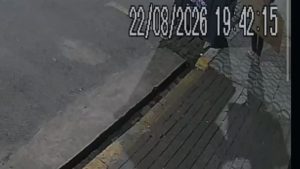 Imagem de uma cena em ambiente industrial, com câmera de segurança apontando para uma área com estrutura metálica e piso de concreto, exibindo marcação de data e hora no topo.