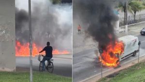 Ambulância pega fogo Itanhaém em uma avenida de Itanhaém, SP, após sair de oficina, com chamas altas e fumaça visível, enquanto pessoas observam o incidente