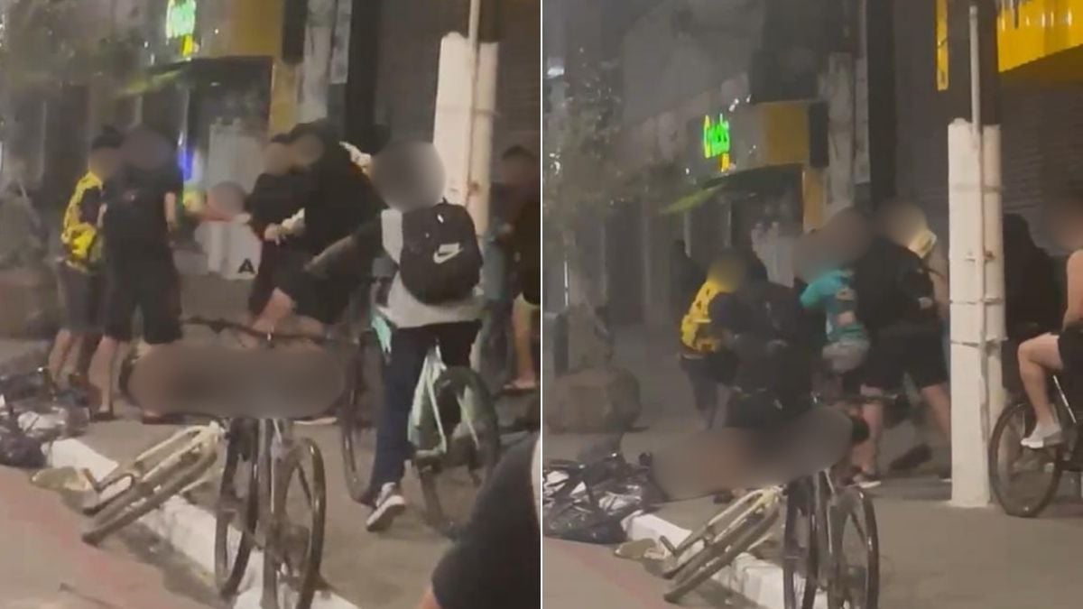 Vídeo de jovem é espancado em Guarujá: cena noturna em avenida, com grupo agredindo uma pessoa enquanto bicicletas ficam ao fundo
