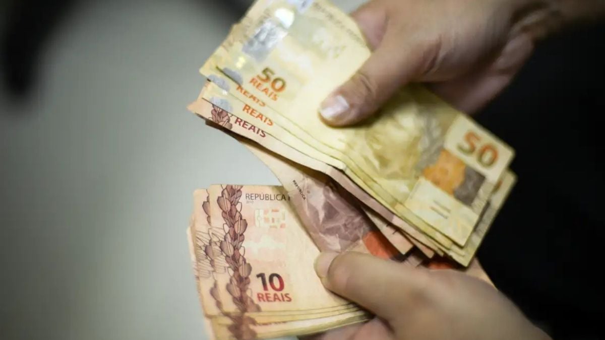 Pessoa contando cédulas de reais, com imagem relacionada ao pagamento e ao prazo do quinto dia útil de setembro.