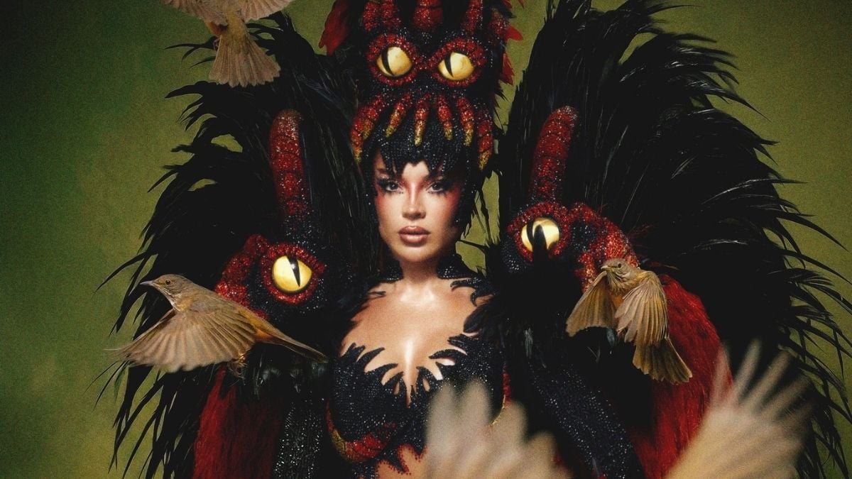 Gkay em foto no Carnaval 2026, posando como musa do Salgueiro, com maquiagem marcante e fantasia de ave com penas e detalhes vermelhos e dourados.