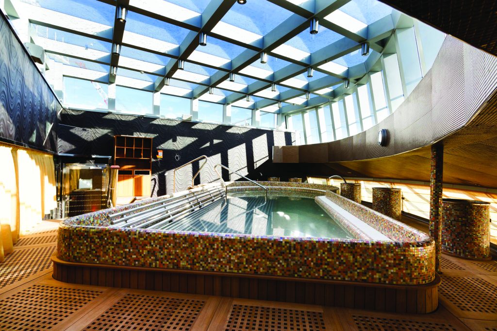 Costa Diadema: piscina ao ar livre em um navio de cruzeiro, com janelas panorâmicas, teto retrátil e deck com espreguiçadeiras e áreas laterais, ideal para temporada de cruzeiros 2026/2027.