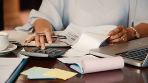 Pessoa analisando documentos e boletos ao lado de calculadora e notebook em uma mesa, tema sobre responsabilidades e regras em condomínios, com foco em evitar prejuízos