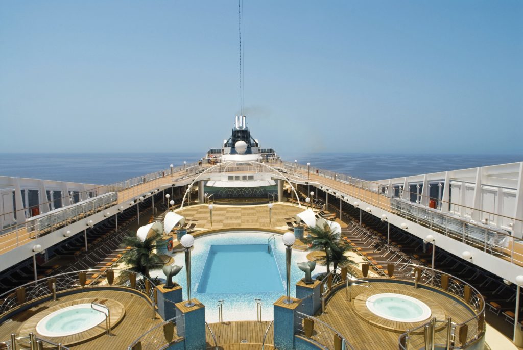 temporada de cruzeiros 2026/2027: Vista da piscina e da área do MSC Musica, com mesas no convés e espreguiçadeiras, mar ao fundo e estrutura do Laguna Bar ao lado.