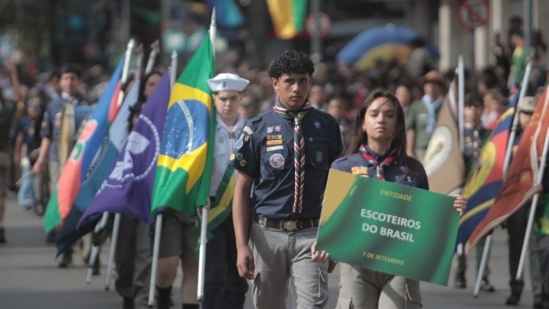 Desfile cívico Campinas no 7 de setembro, com jovens e bandeiras do Brasil ao fundo em uma marcha cívica na cidade.