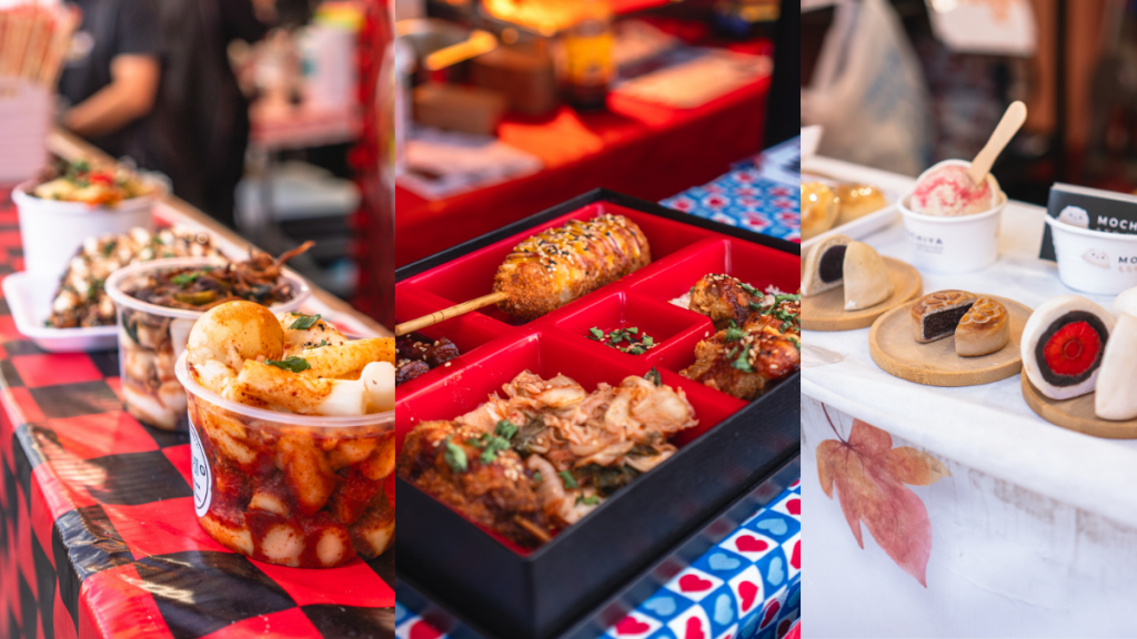 Mesa com comida coreana e pratos em potes e caixas, incluindo frango empanado e porções de petiscos, em evento com bandejas e utensílios de servir.