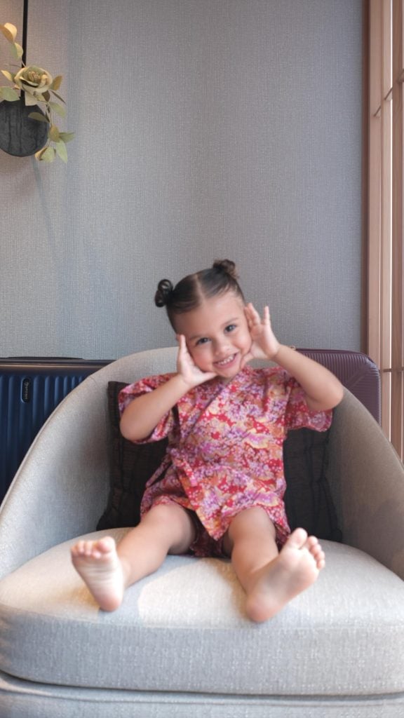 Neymar e filha helena: helena sorridente em um sofá faz uma careta, repetindo um gesto parecido com o do pai em um ambiente interno com luz natural.