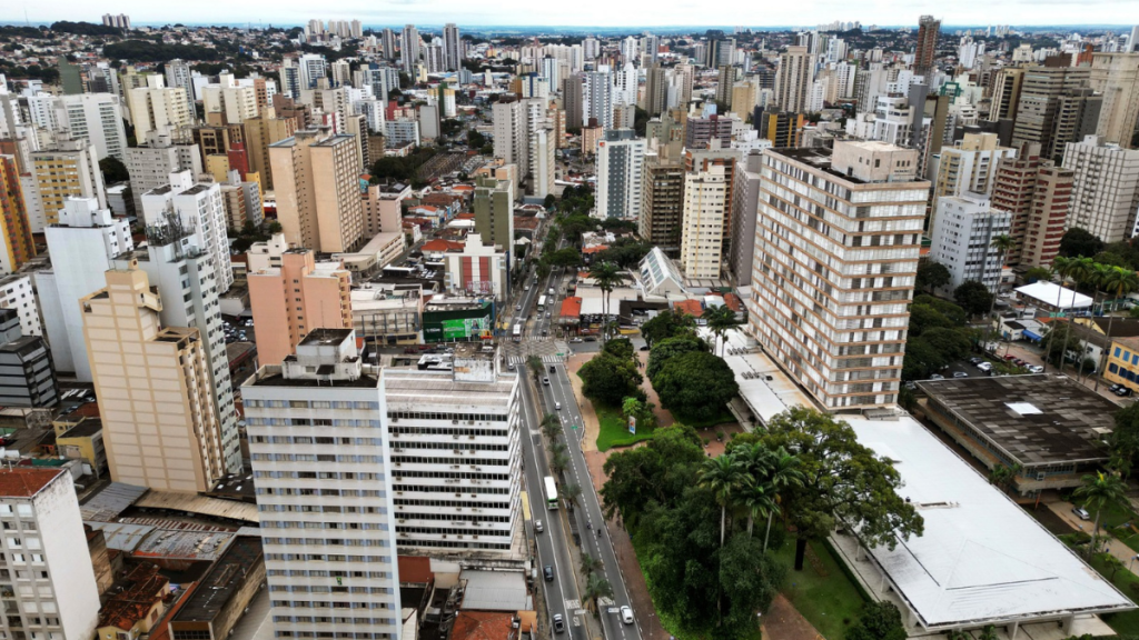 Vista aérea de Campinas com edifícios e torres residenciais e comerciais, com ruas ao centro e áreas verdes entre os prédios