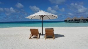 Feriado prolongado está chegando: praia de Santos com guarda-sóis e cadeiras ao sol, destacando as datas de 7 de setembro nacional e 8 de setembro em Santos.