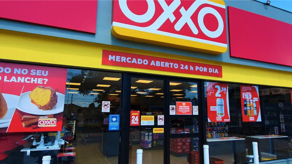Fachada de uma loja da rede Oxxo com placa “Mercado aberto 24h por dia” e cartazes na entrada, em imagem relacionada a oxxo segurança e reforço de proteção após condenação trabalhista.
