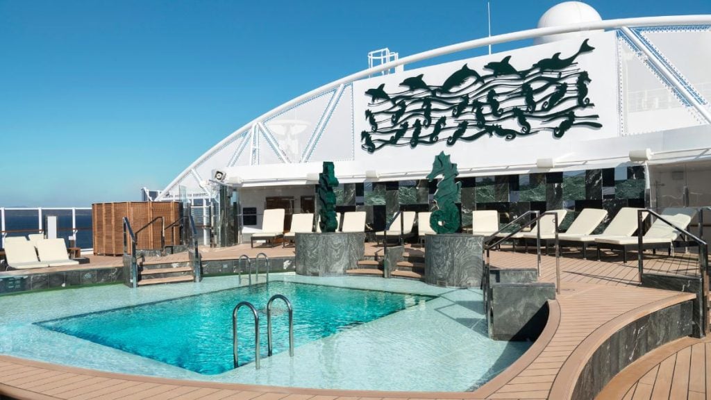 MSC Cruzeiros em Santos: Piscina exclusiva do MSC Yacht Club no MSC Seaview, com deck de madeira, espreguiçadeiras e vista para o mar em um ambiente de cruzeiro de luxo.